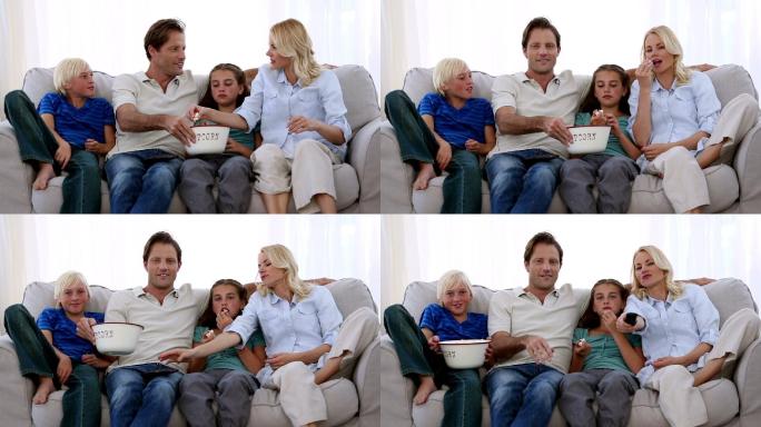 家人坐在沙发上看电视吃爆米花特写