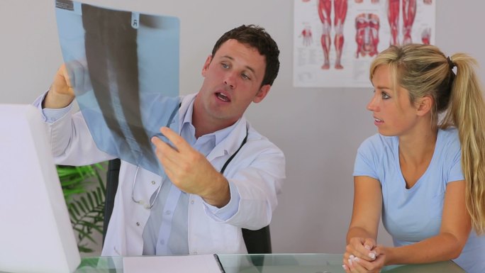 脊椎按摩师和他的病人讨论并给她看一张x光片