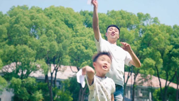 爸爸和小孩子飞纸飞机父子草地玩耍空镜头