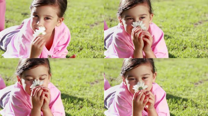 小女孩手捧一朵美丽的花，躺在草地上