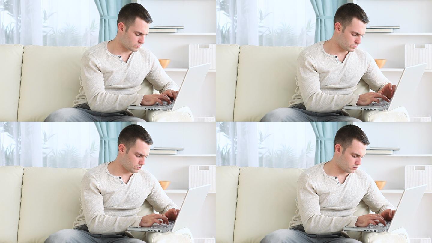 一个男人坐在沙发上用电脑工作特写