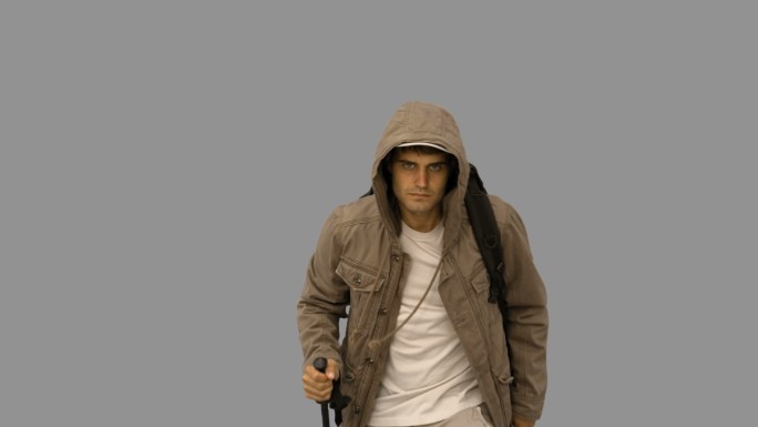 一个穿着大衣的英俊男子在灰色屏幕上用慢动作徒步旅行