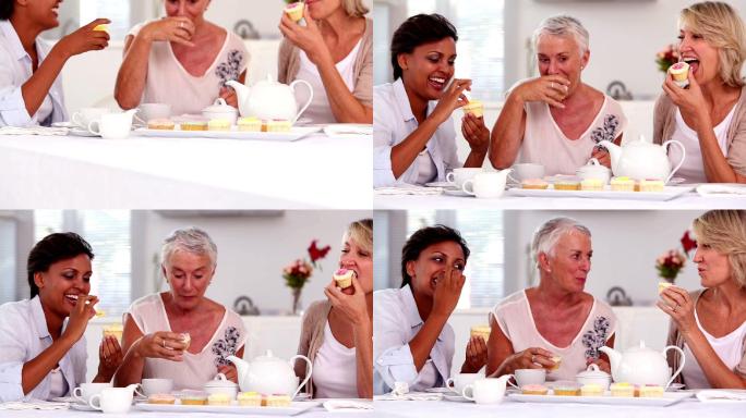 退休妇女在家里的厨房里一起吃纸杯蛋糕喝茶
