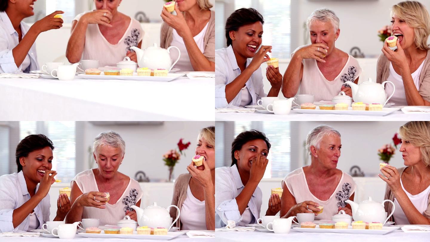 退休妇女在家里的厨房里一起吃纸杯蛋糕喝茶