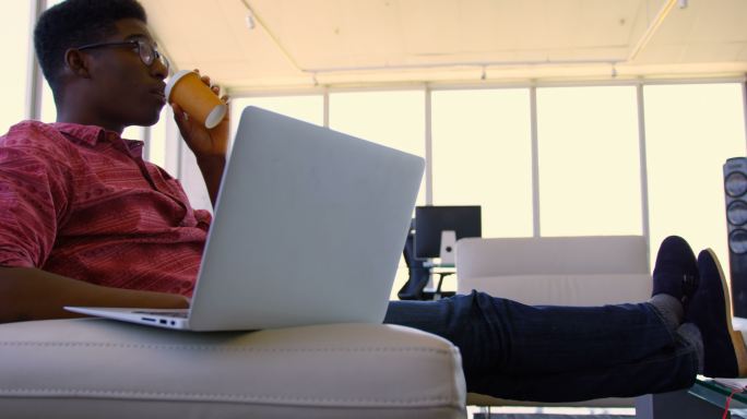 英俊的非裔美国男性行政人员使用笔记本电脑在现代办公室4k