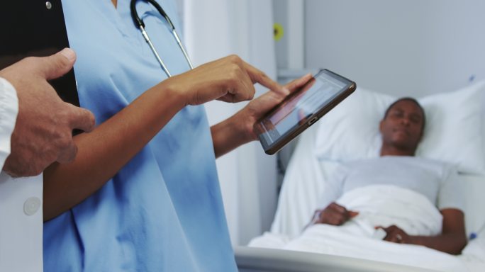 特写的多民族医生讨论x光报告的数字平板电脑在医院病房