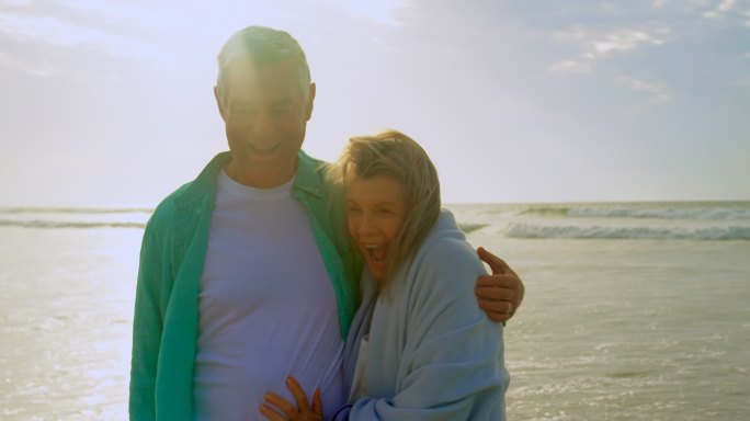 活跃的白人老年情侣在沙滩上拥抱