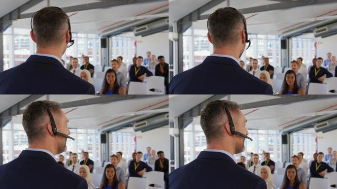 在一场商业研讨会上，男性演讲者戴着耳机向听众讲话