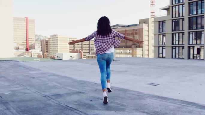 时尚的年轻女子在城市的屋顶上奔跑