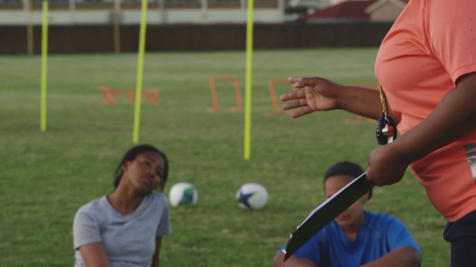 年轻的成年女子橄榄球队与教练训练