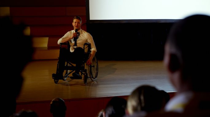 年轻的白人残疾商人在商务研讨会上演讲在4k大礼堂