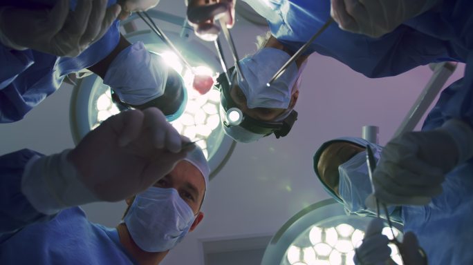 多民族外科医生在医院手术室进行手术的上行视图