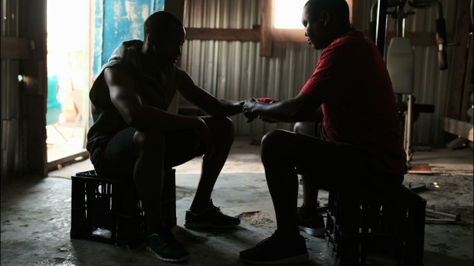非裔美国男教练协助拳击手在佩戴手包在健身房4k