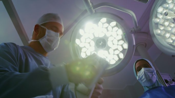 白种人外科医生在医院手术室对病人使用除颤器的低视角观察