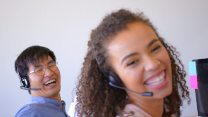 快乐的多民族客户销售主管在现代办公室通过耳机交谈4k