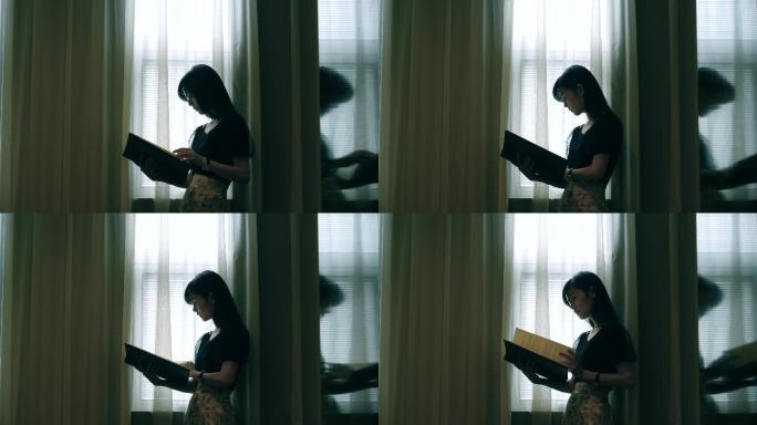 女孩在窗边翻看画册书籍4k视频素材