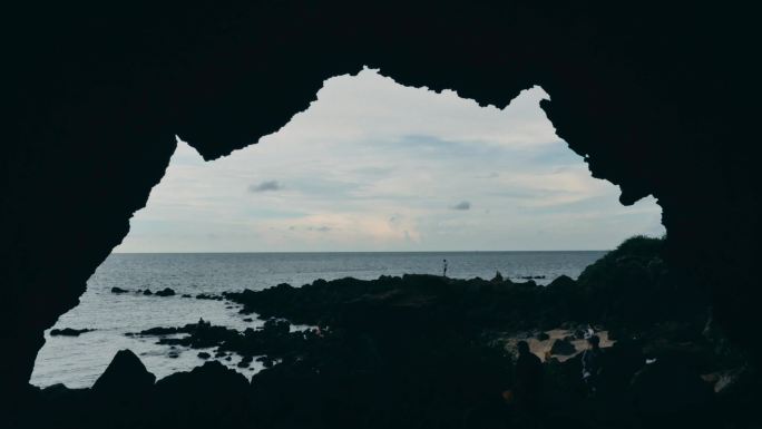 游客在苍穹岩石下的海边游玩儋州龙门激浪