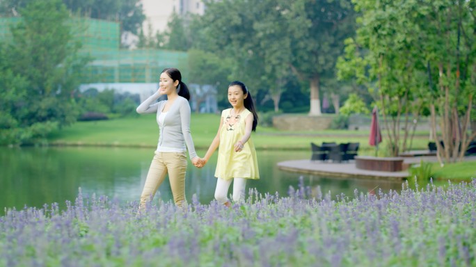 妈妈女儿母女二人草公园草地湖边散步