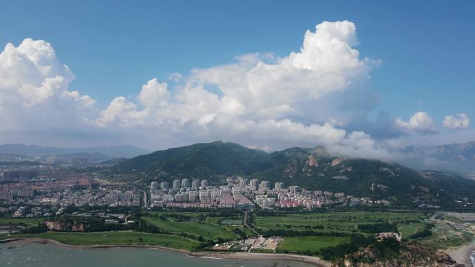 航拍青岛崂山蓝天白云草地海边风光