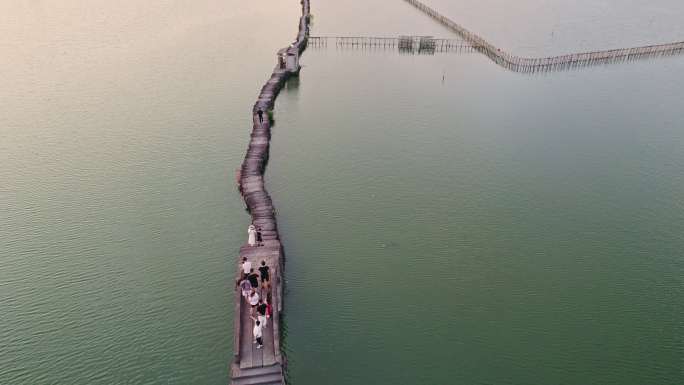 晚霞自然风光水上石板长桥上的游客