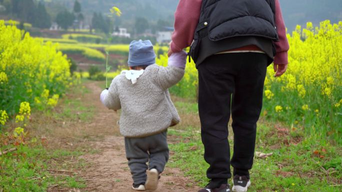 土路上妈妈拉着孩子行走