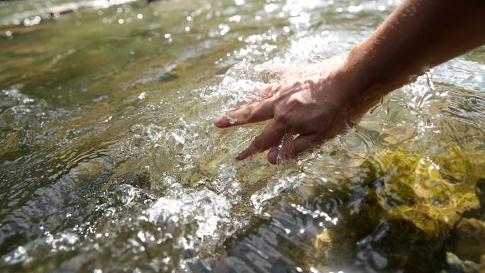 手抚摸清澈泉水溪流亲近自然
