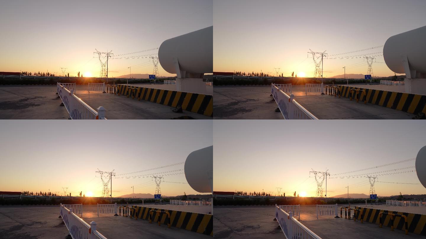 夕阳下高压电线塔附近巨大的储气罐航拍
