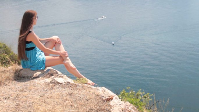 乌克兰克里米亚巴拉克拉瓦，一名年轻女子在岩石上眺望黑海