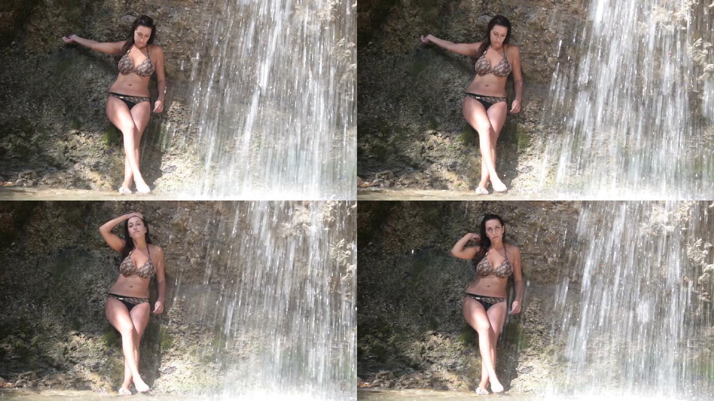 穿着比基尼的迷人年轻女子，享受着瀑布带来的凉爽。
