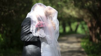 新郎在公园小巷亲吻戴着面纱的新娘视频素材