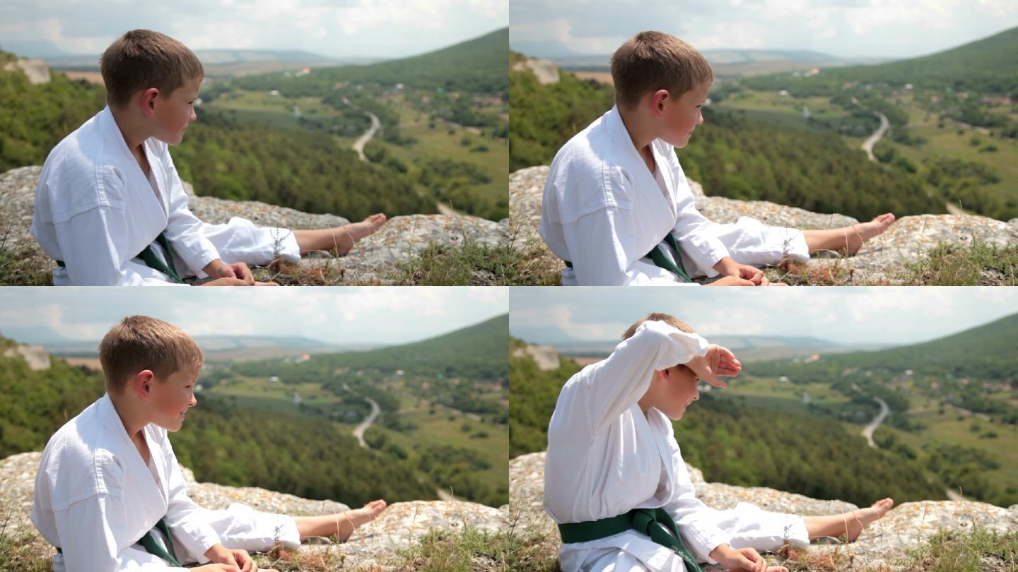 穿着和服的男孩坐在悬崖边休息