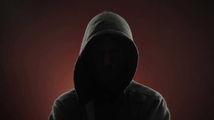 一个戴着头巾的匿名威胁暴徒盯着红色背景前的摄像机。也可提供偏心版本。