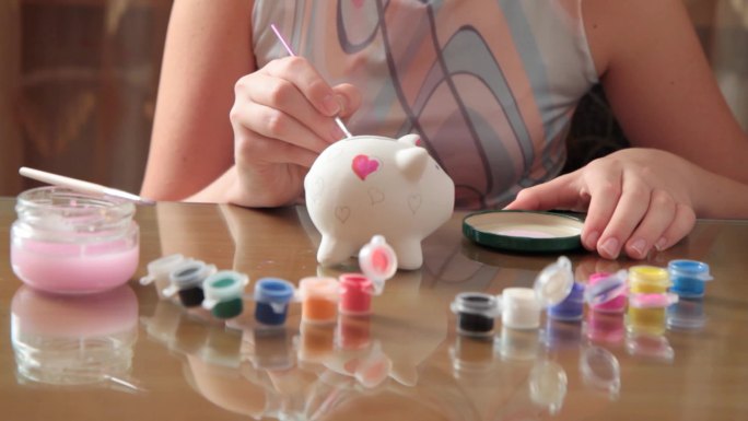 女孩画猪硬币盒。