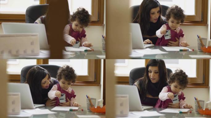 妈妈和女商人在家里用笔记本电脑工作，和她的女婴玩耍