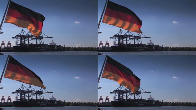德国国旗挂在蓝天前，背景是Krsne和集装箱船。