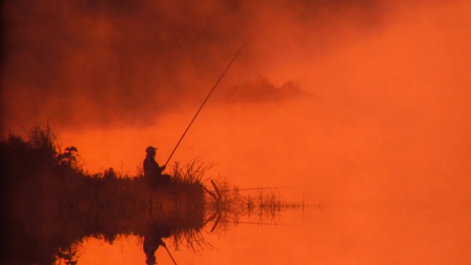 渔夫清晨在雾蒙蒙的湖面上。