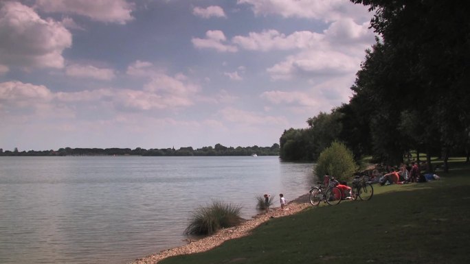 坐在湖岸上的成年人和向水中扔石头的儿童