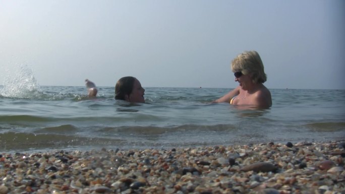 女儿和妈妈快乐地躺在海水里。