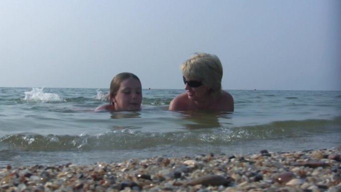 女儿和妈妈快乐地躺在海水里。