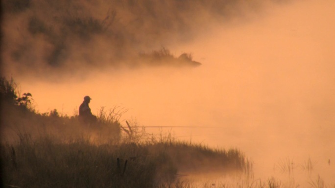 渔夫清晨在雾蒙蒙的湖面上。