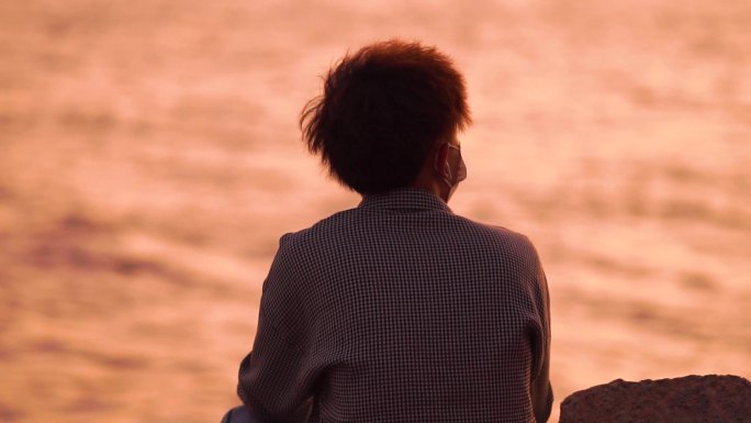 夕阳海边男性坐着的背影