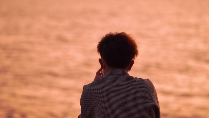海边男性看手机的背影