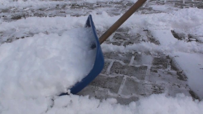 人用雪铲在人行道上滑行