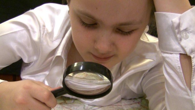 拿着放大镜的女孩研究欧洲地图。