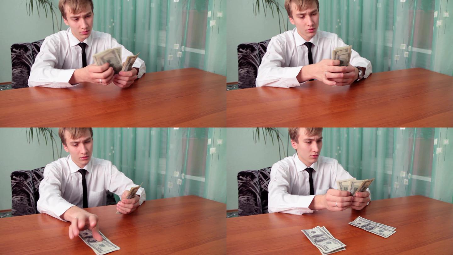 这个年轻人坐在办公室的桌子旁分钱。