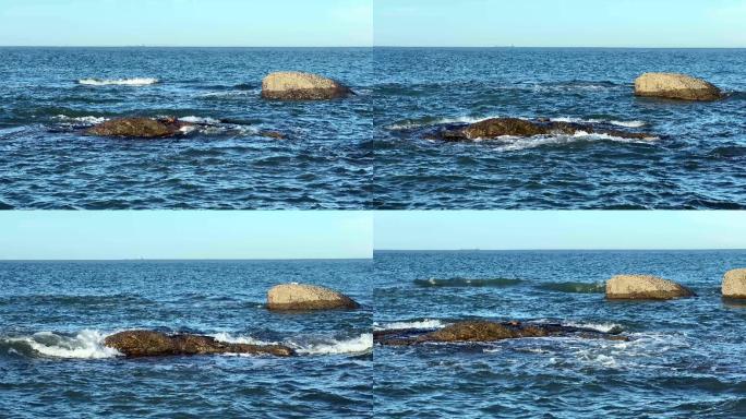 深蓝色海平面海浪和礁石远处轮船