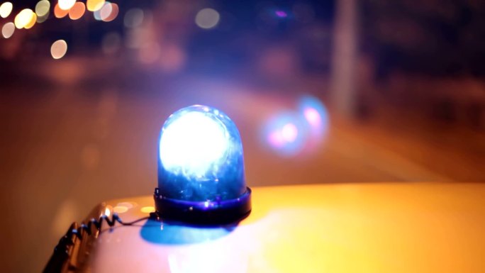 夜间城市街道上行驶的警车车顶上的蓝色应急灯