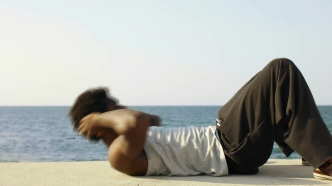 古巴哈瓦那，年轻的黑人男子沿着加勒比海做一系列仰卧起坐