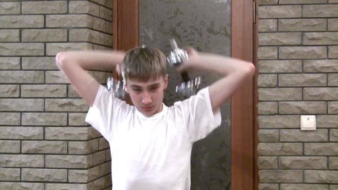 十几岁的男孩用哑铃锻炼身体。