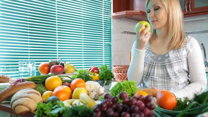孕妇在厨房里吃很多蔬菜和水果附近的苹果